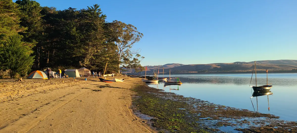 Campsite in the morning light with TSCA boats on the water